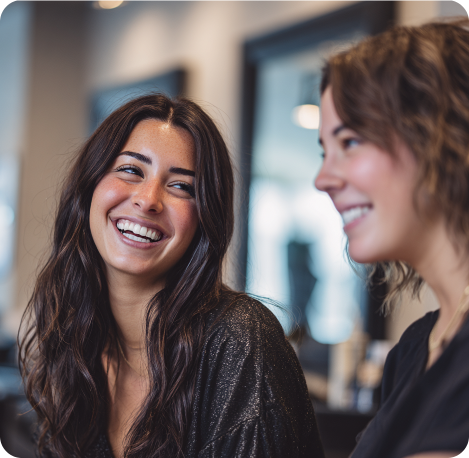 Two friends laughing together at a salon